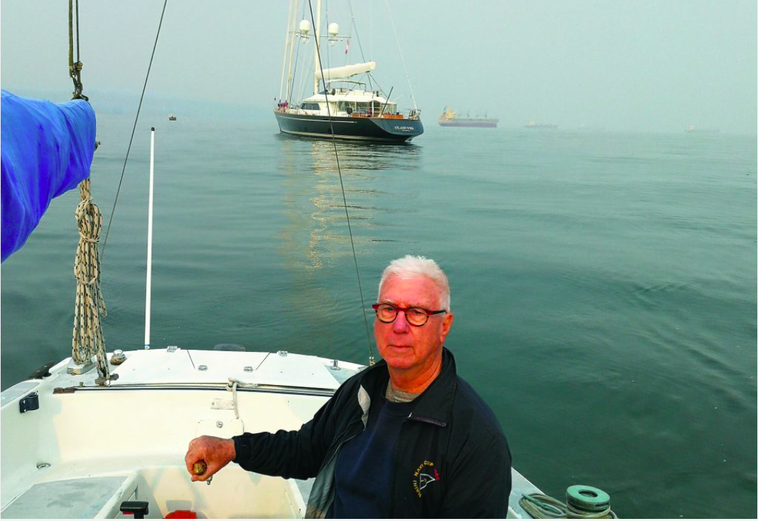 Yacht Designer, Ron Holland sailing on Kia Aura, with his design sailing yacht Clan V in background in Burrard Inlet, Vancouver, BC, Canada