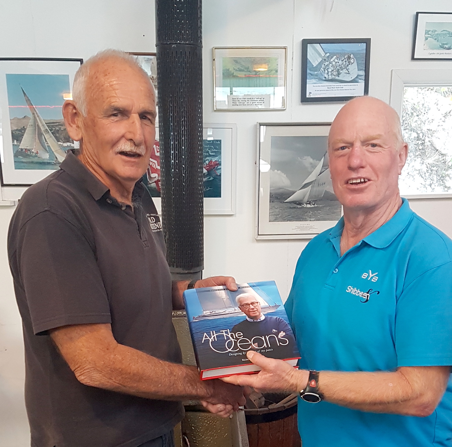 Willie Newman Little Ship Club Canterbury presents Commodore Colin Lock of Naval Point Club Lyttelton a copy of Ron Holland's memoir All The Oceans for the club library