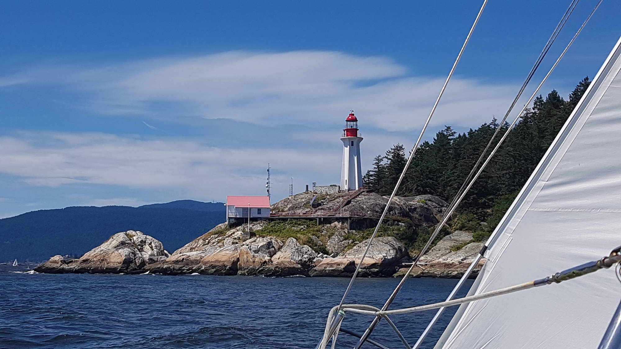 Historic Point Atkinson Lighthouse with a peek of the sheet on Kia Aura sailing past on a summer day