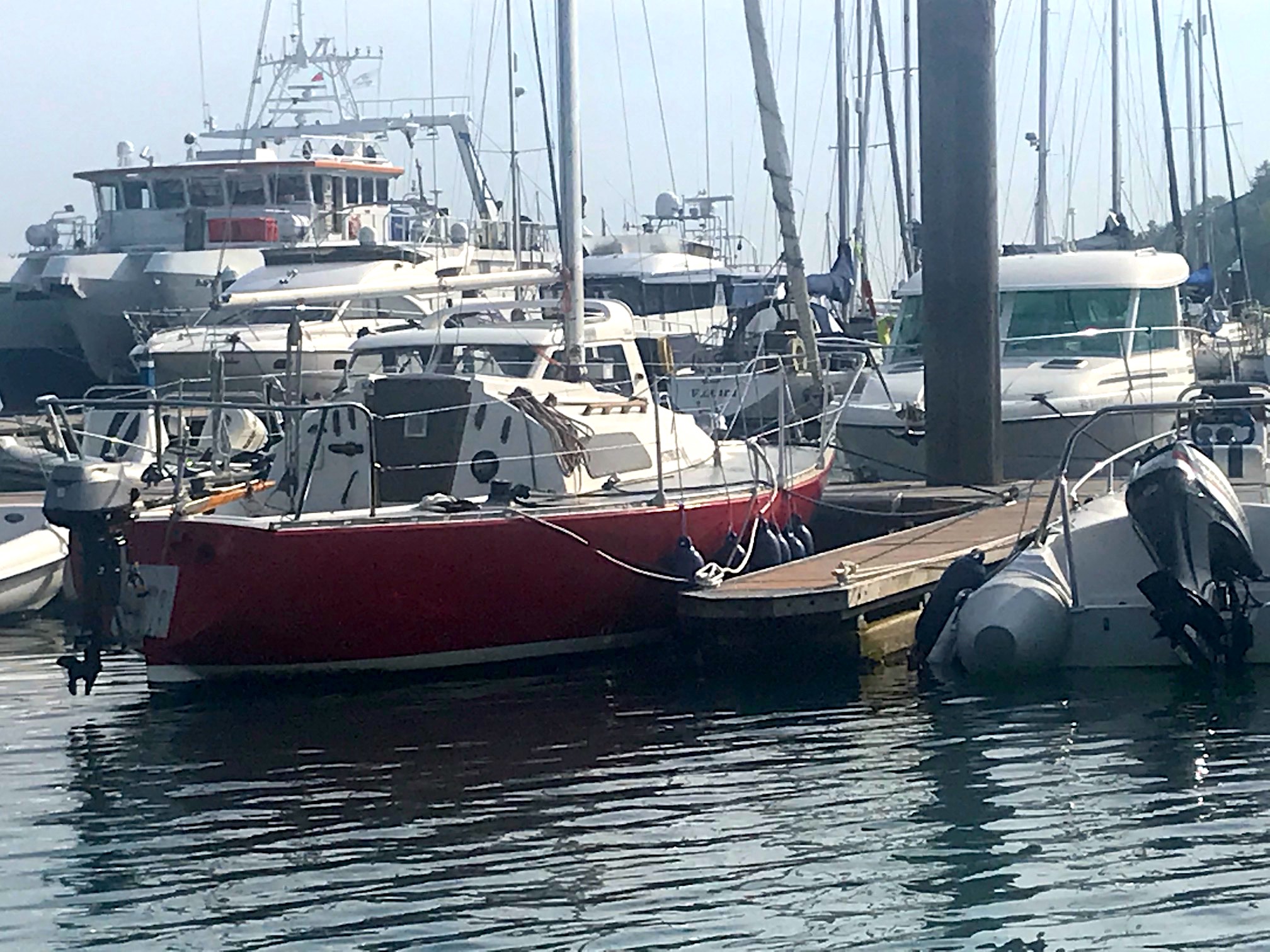 Red hull of Eygthene 24 the iconic Ron Holland Design race boat moored at marina, photo credit Neil Kenefick