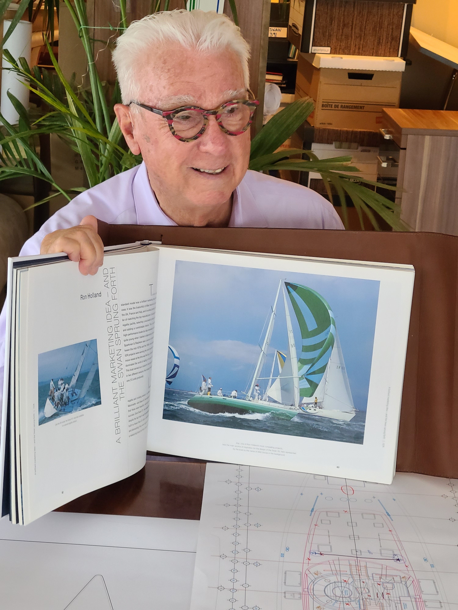 Ron Holland displays the Swan Book of Yachts with the legendary "imp" with green striped spinnaker showing in photo